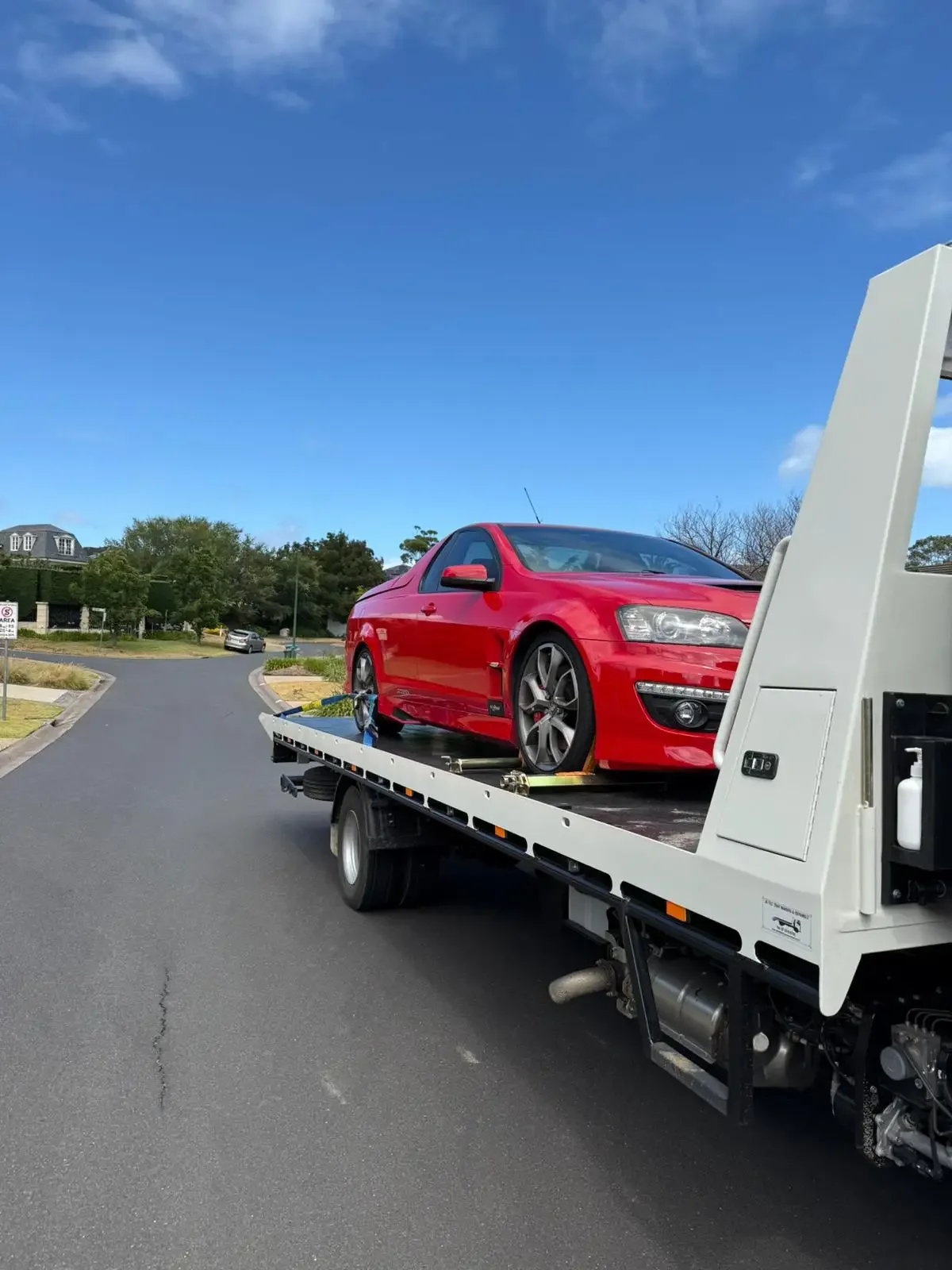 Red Holden ute strapped onto a white tilt-tray truck