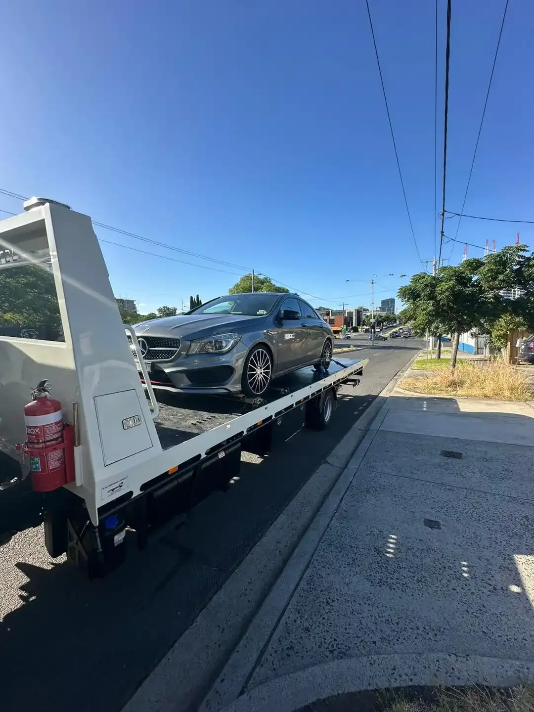Grey Mercedes-Benz sedan on a tilt-tray truck at the kerb