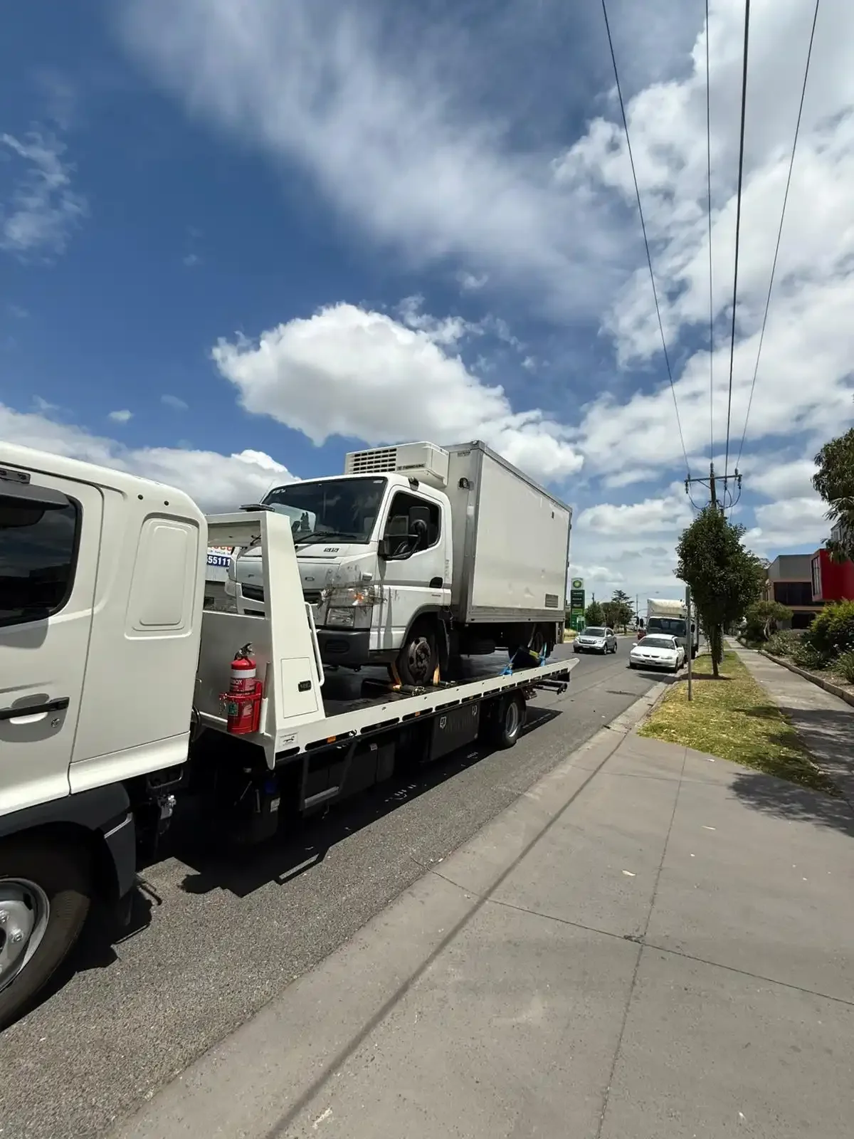 Small refrigerated truck carried on the back of a tilt-tray truck